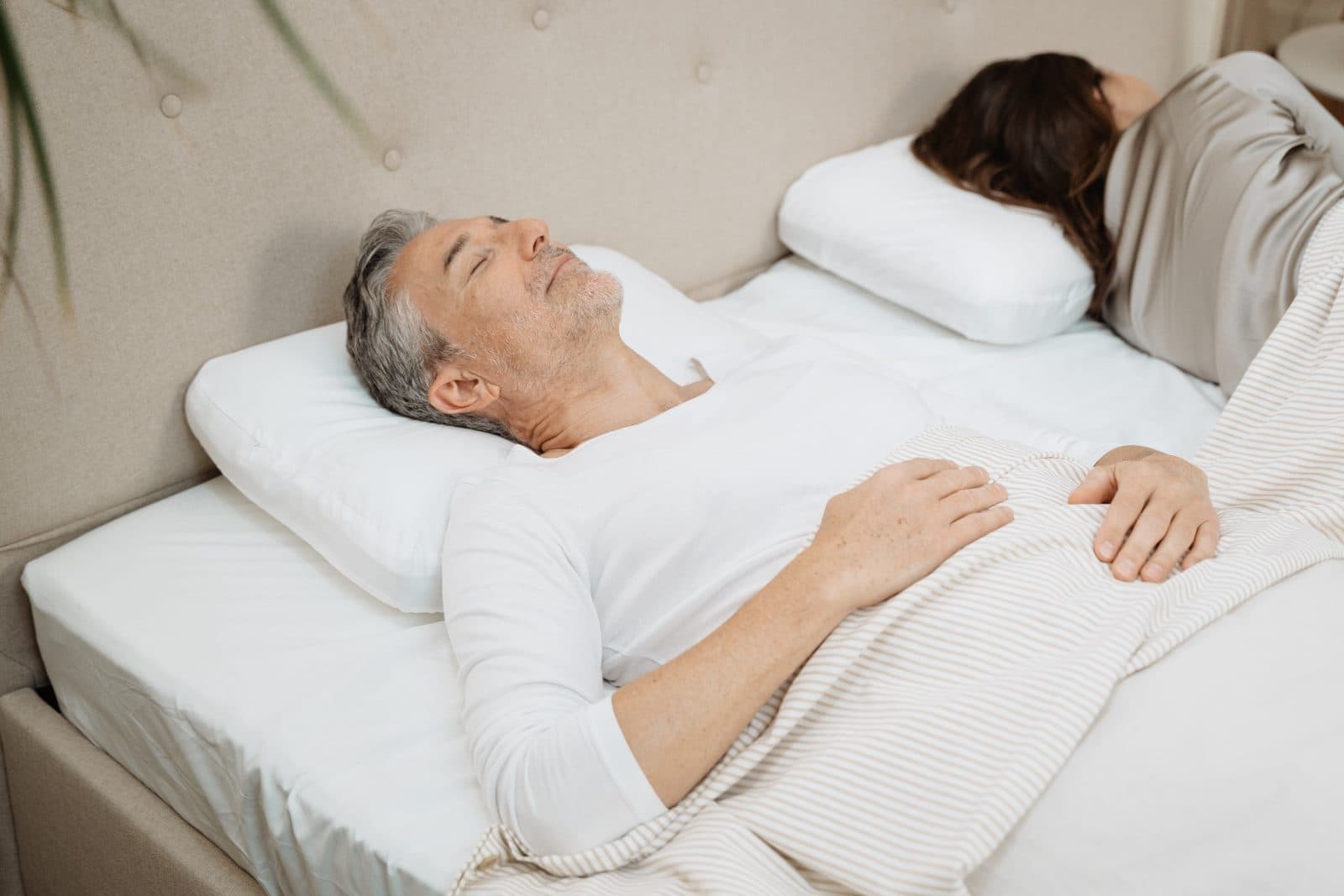 Mann schläft zufrieden neben seiner Partnerin im Bett