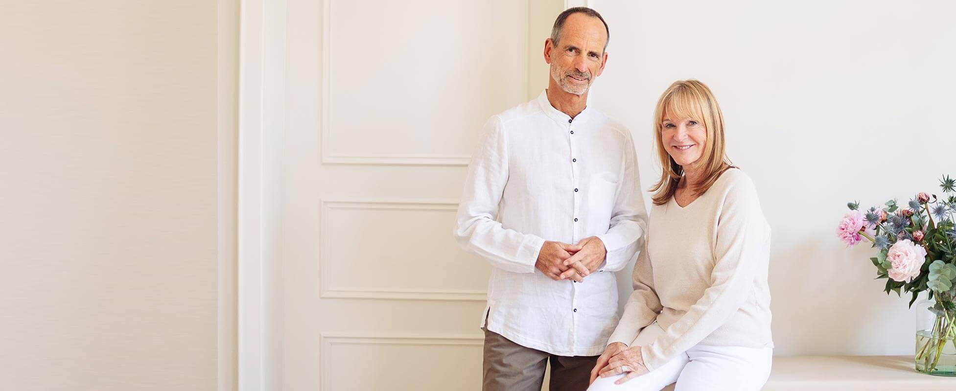 Roland is standing next to Petra who is sitting and both are smiling into the camera
