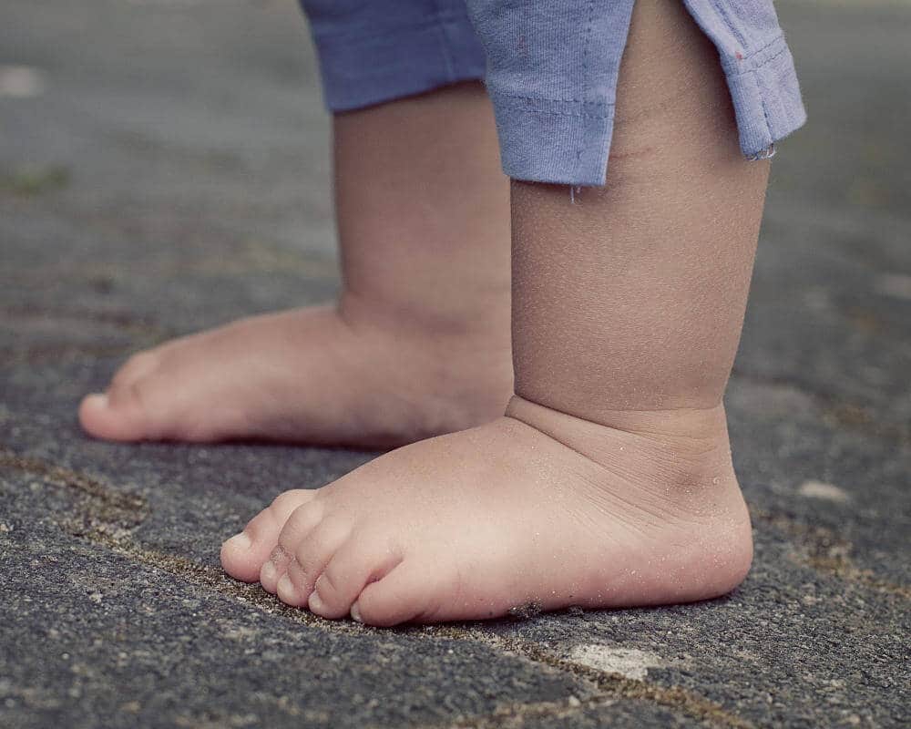 A little child's feet on asphalt.