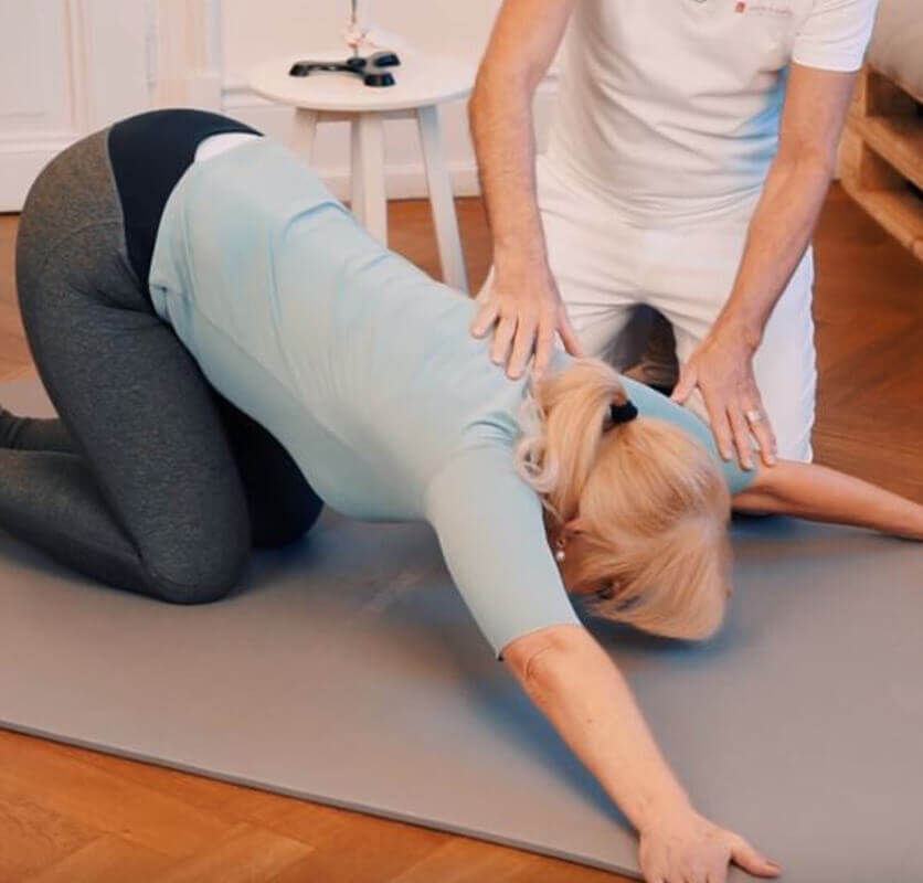 Woman kneeling on the ground with the arms stretched out on the floor and her face turned downwards.