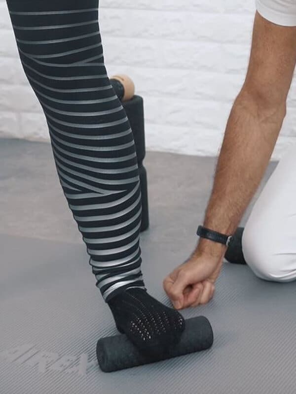 Woman performing an exercise against hallux valgus using a fascia roll.