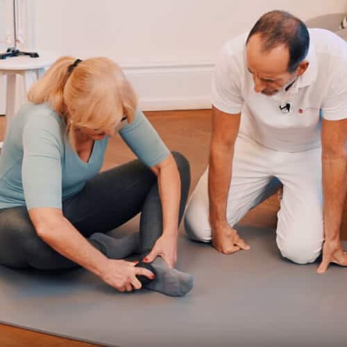 A woman is using a fascia ball on her heels.