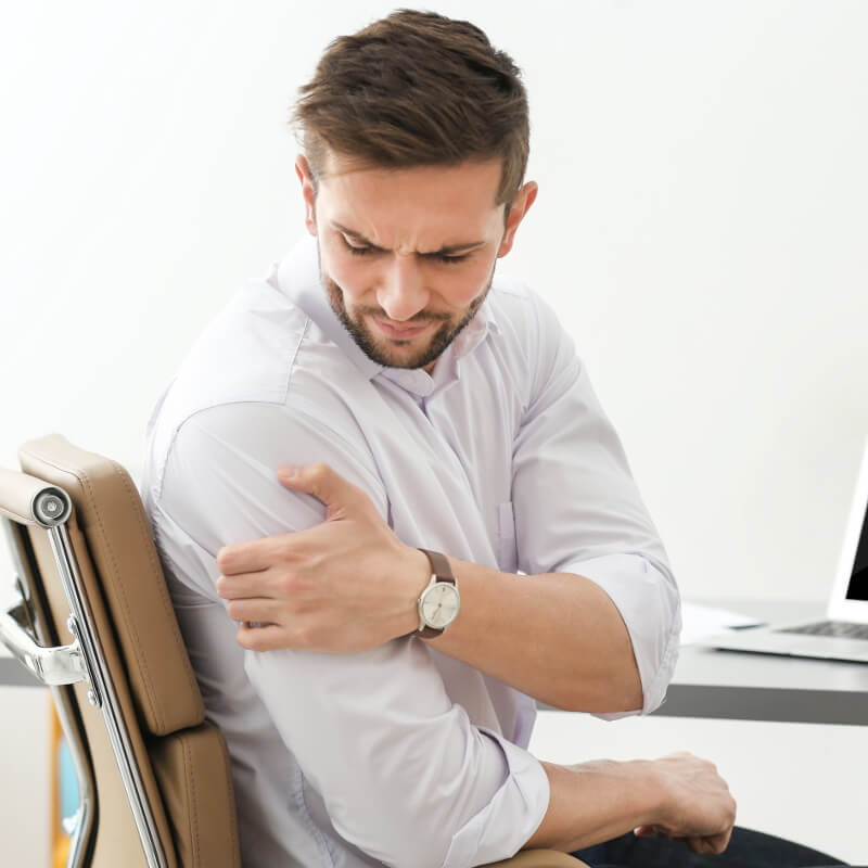 A man clutching his shoulder, grimacing in pain.