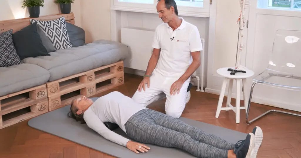 A woman is lying on an exercise mat on her back.