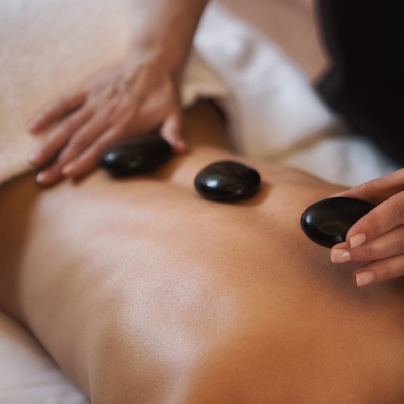 Three black hot stones on a person's back.