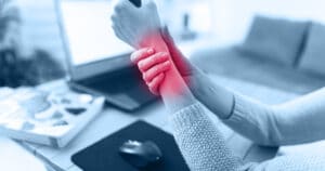 A woman is grasping her hurting wrist.
