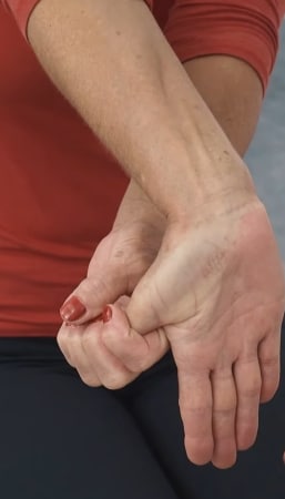 A woman is pulling her left thumb backward.
