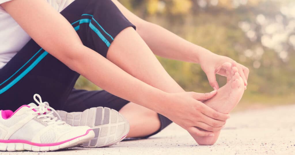 A woman is holding her hurting foot.