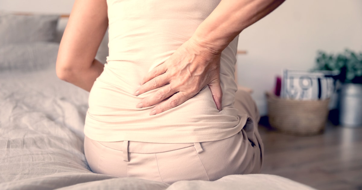 A woman is holding her hurting lower back.