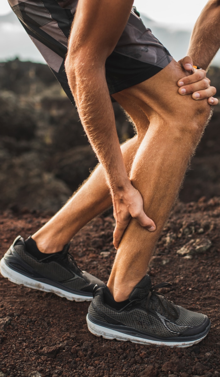 A man is grasping his hurting Achilles tendon.