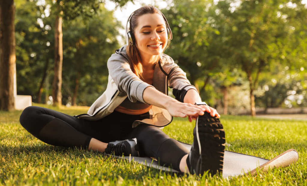A woman is stretching her Achilles tendon and smiles.