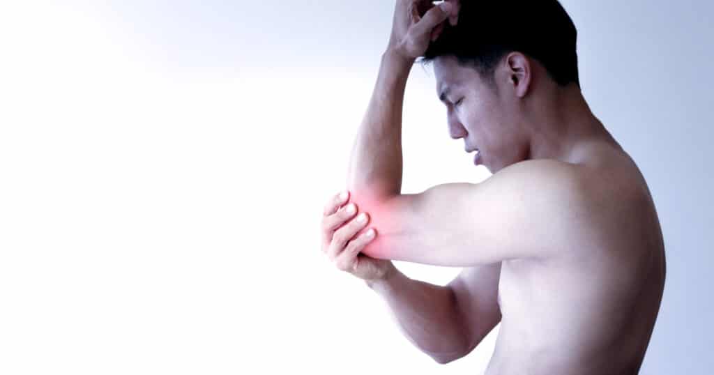 A man is holding his hurting elbow affected by golfer's elbow syndrome.