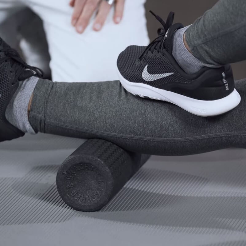 A woman is foam rolling her calves.