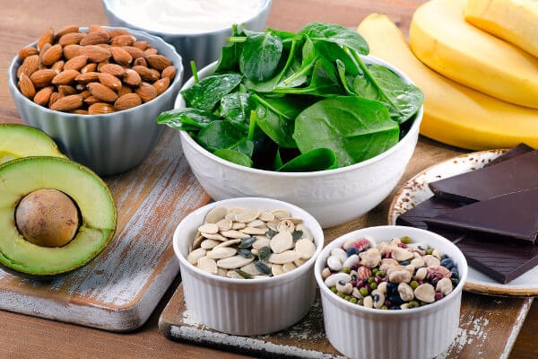 A selection of food containing magnesium: seeds, nuts, avocado, and spinach.