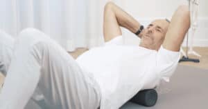 Roland is lying on the ground, massaging himself with a massage ball.