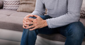 A man is holding his aching knee.