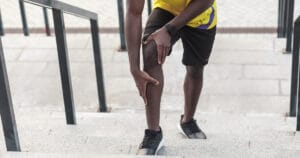 A man clutching his hurting knee.