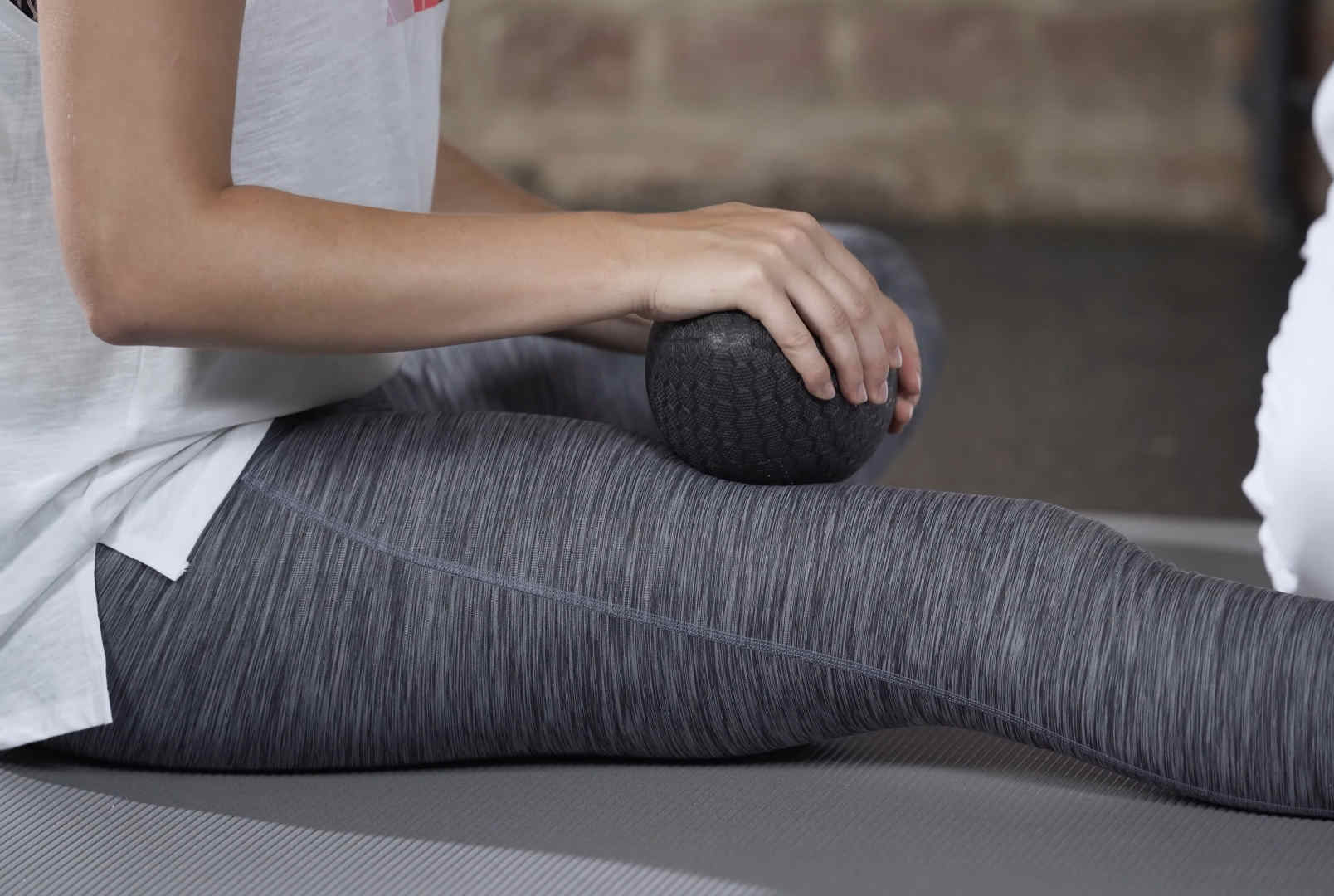 A girl is massaging her thighs with a massage football.