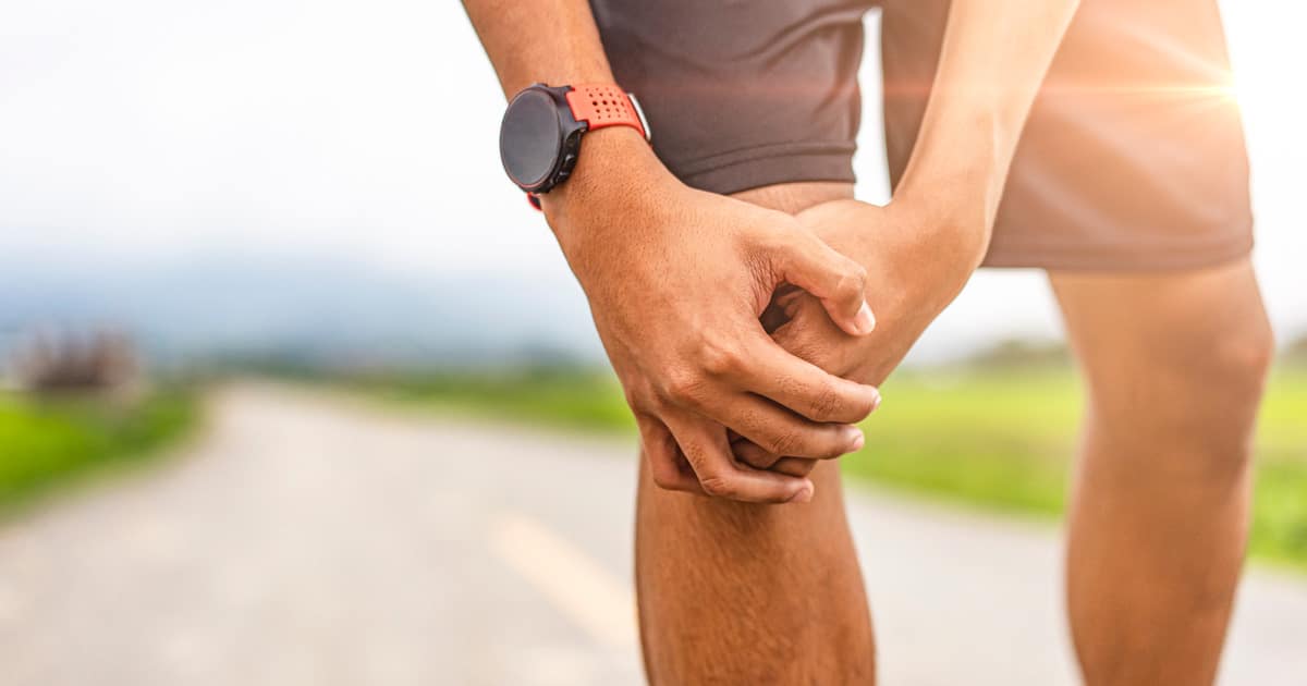 A man is holding his hurting knee. He has a baker's cyst.