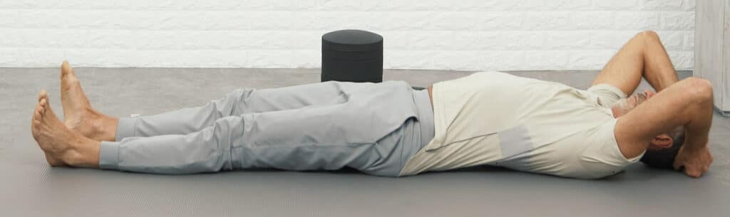 Roland Liebscher-Bracht lies down on a mat, planting his feet on the ground and clutching his head with his hands.