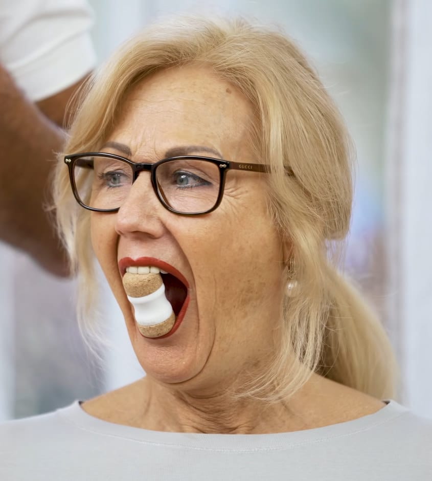 A woman is using the Jaw Hero to stretch her jaws.
