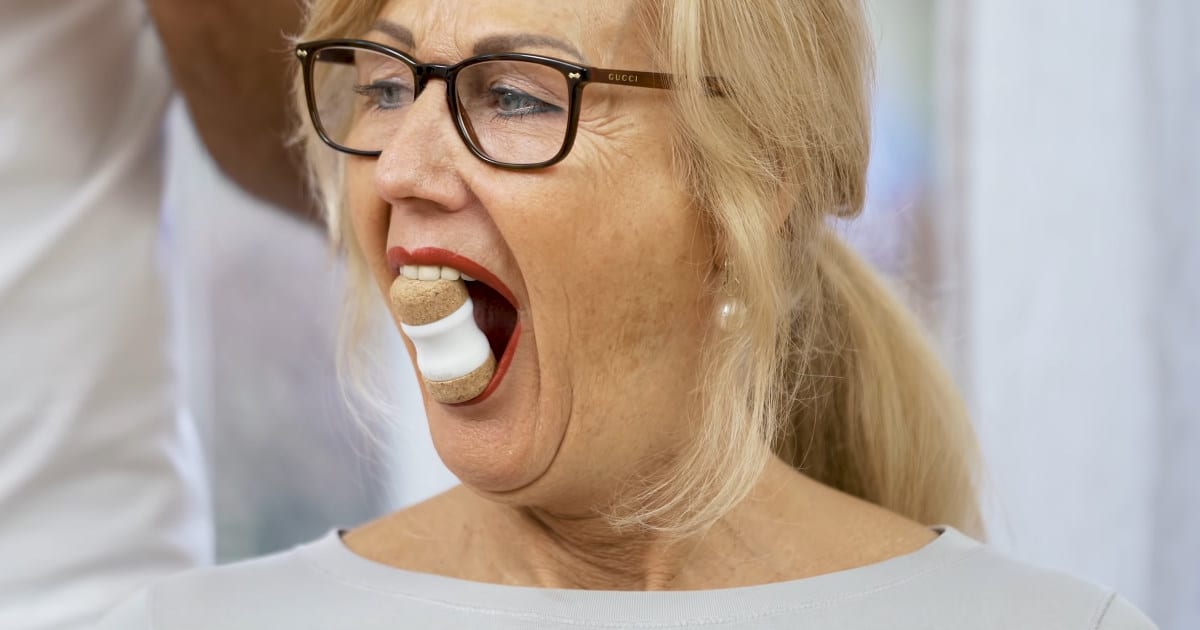A woman is stretching her jaws with the Jaw Hero.