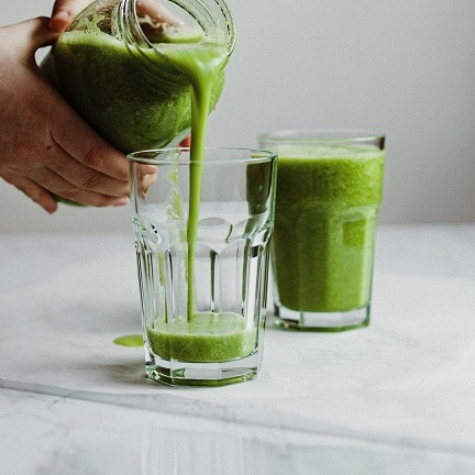 Image of someone pouring green smoothie into a glass; smoothie recipe for osteoarthritis