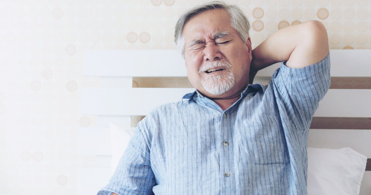 A man is suffering from chest and back pain. He is touching his back with an agonised expression.