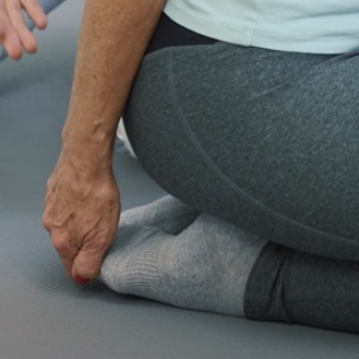 A woman is stretching her big toe.