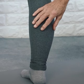A woman is stretching from the top of her calf to the bridge of her foot.
