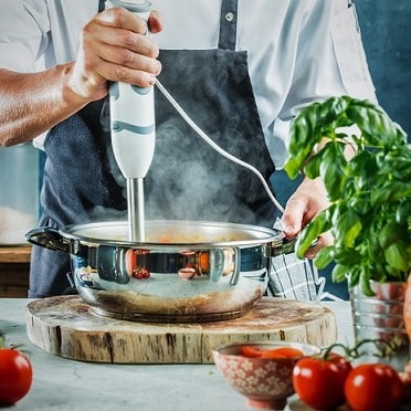 chef with blender blending soup in the kitchen