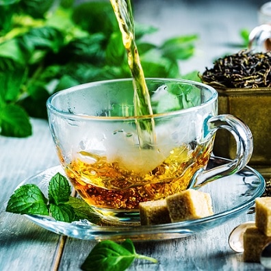 image of hot water pouring into cup with peppermint and loose tea leaves