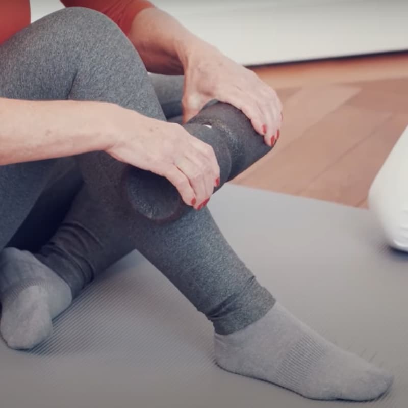 A woman has the Midi Foam Roller on the top of her calf.
