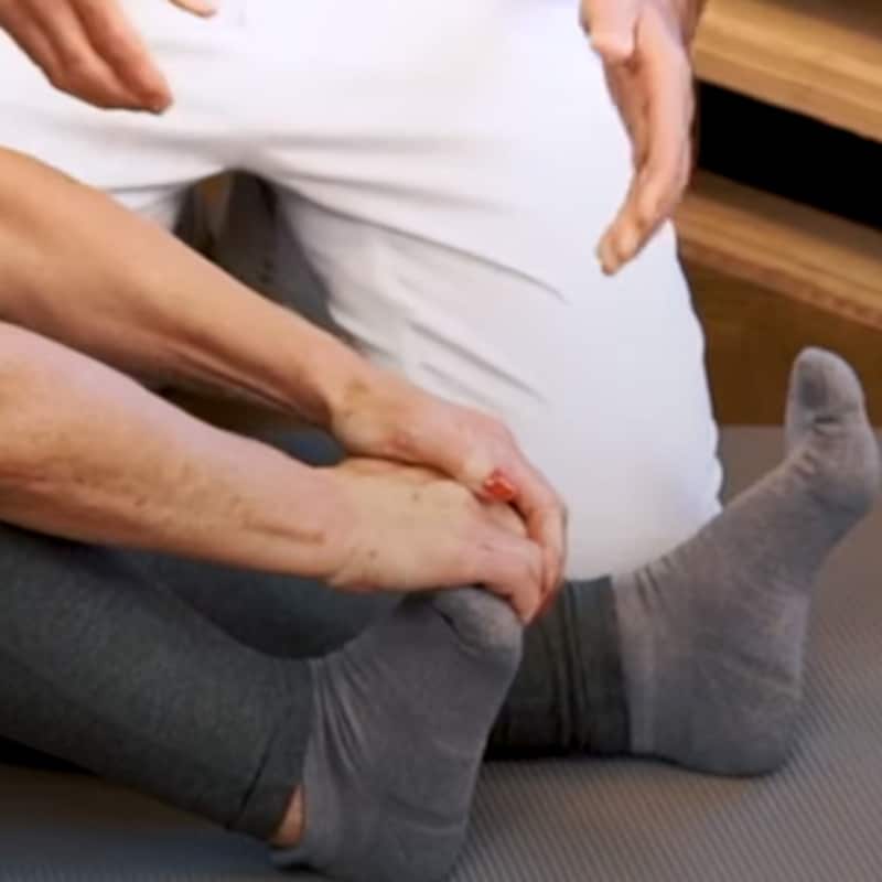 A woman is pulling the toes of her right foot backward.