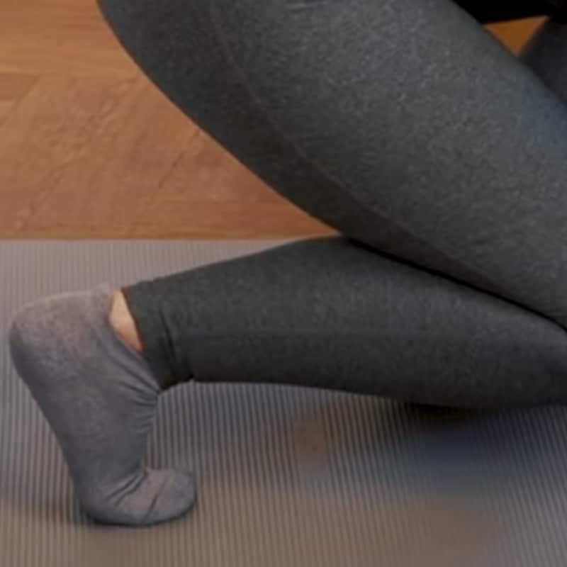 A woman is in runner's position stretching her back foot.