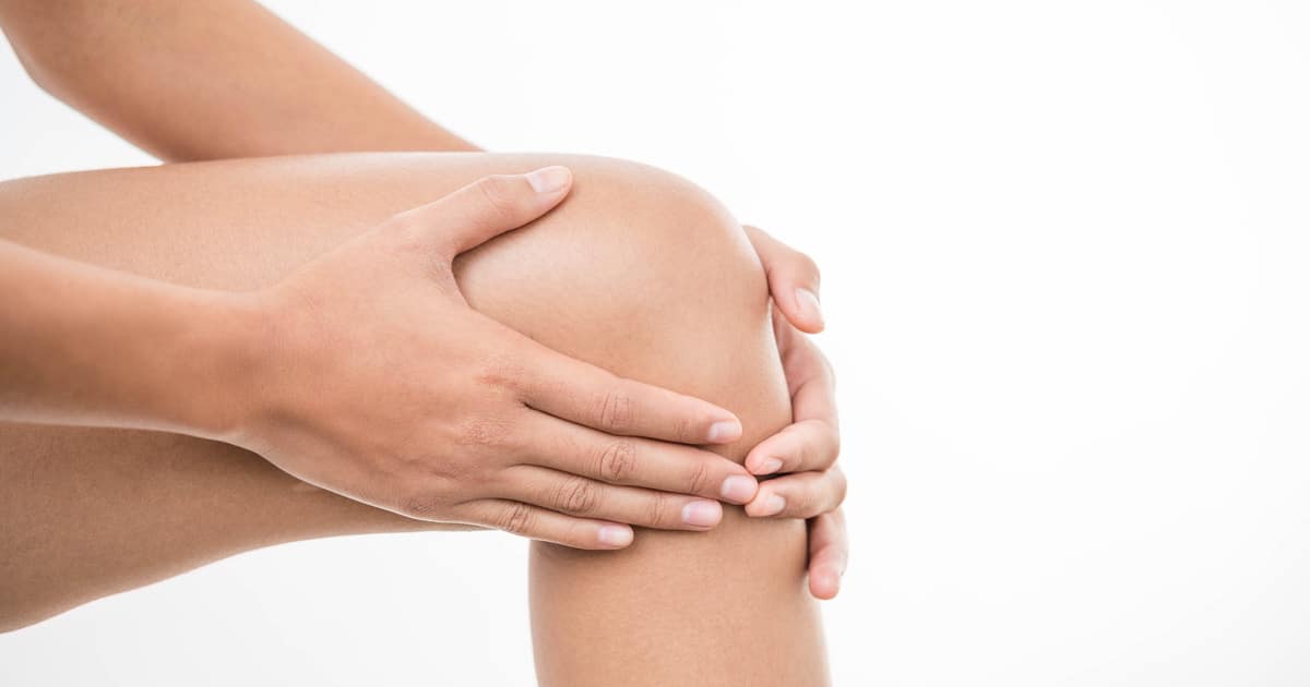 Two hands are touching a cracking knee.