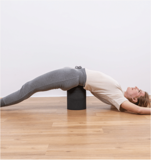 A woman is stretching her back with Liebscher & Bracht's Back Hero.