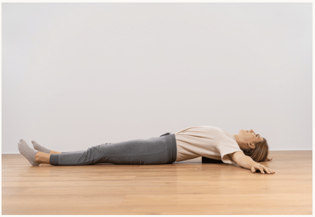 A woman stretches her chest area by lying on the Liebscher & Bracht back hero and extending her arms to both sides
