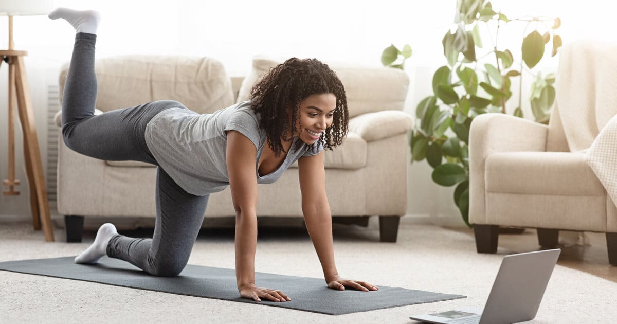 A woman in front of a laptop doing some exercises.