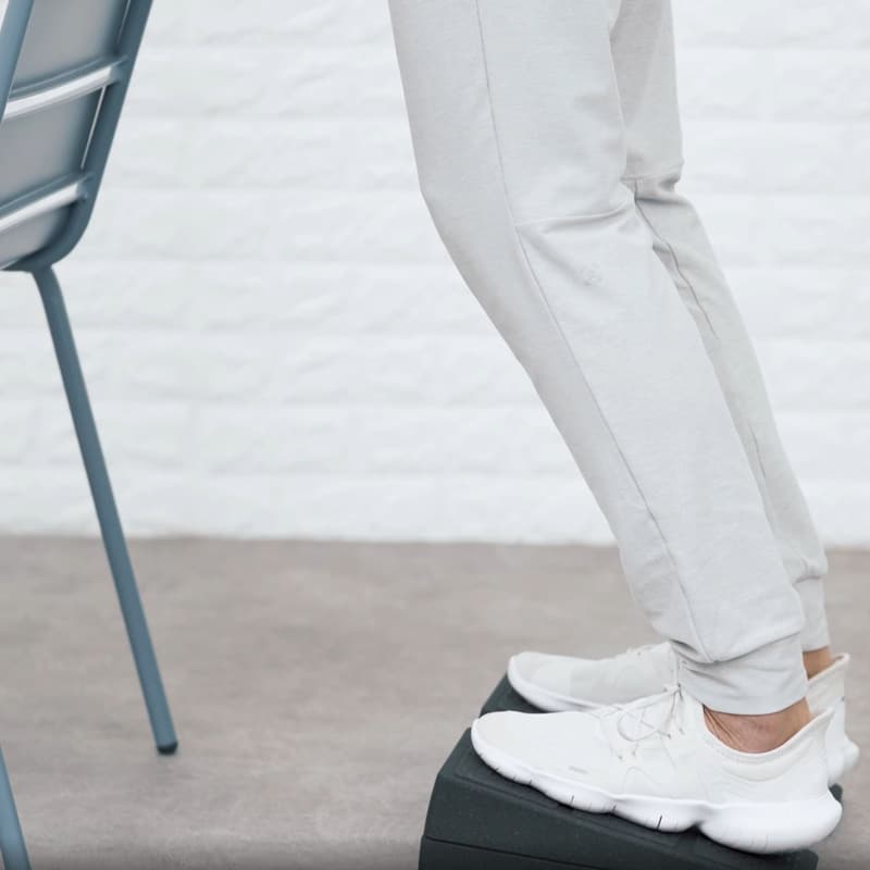A man is stretching with the Knee Hero to relieve patellar tendonitis.