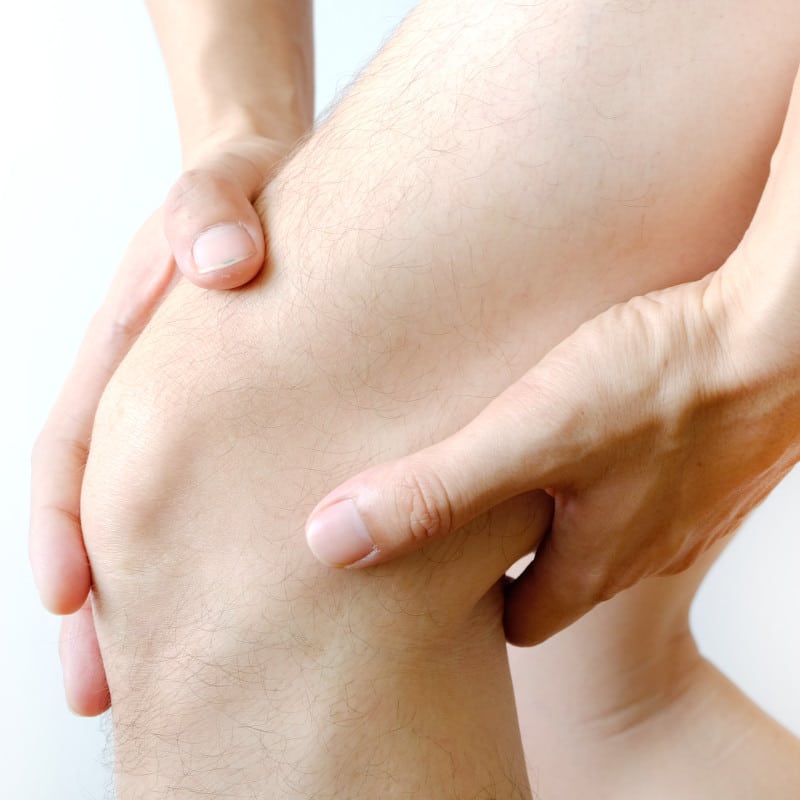Closeup of a man touching the front and back of his knee.