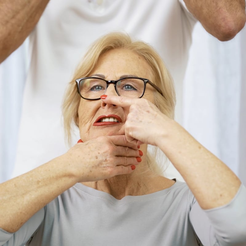 A woman has one hand on her chin and her index finger on the tip of her nose.