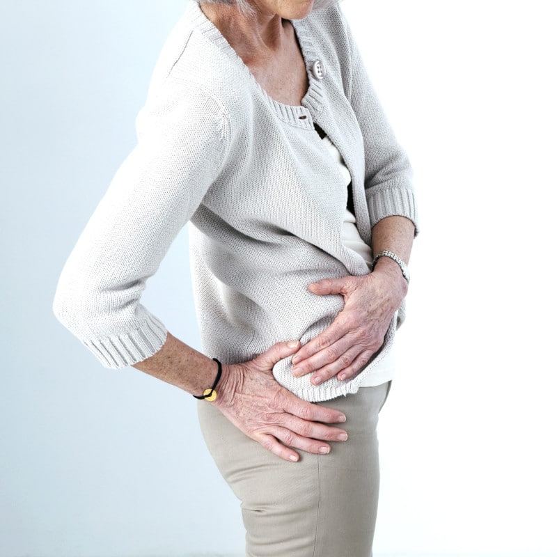 Close-up of a woman touching her affected hip.