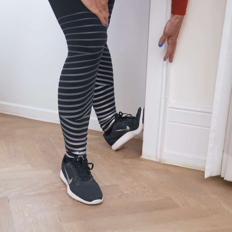 A woman has wedged the ball of her foot against a door jamb.