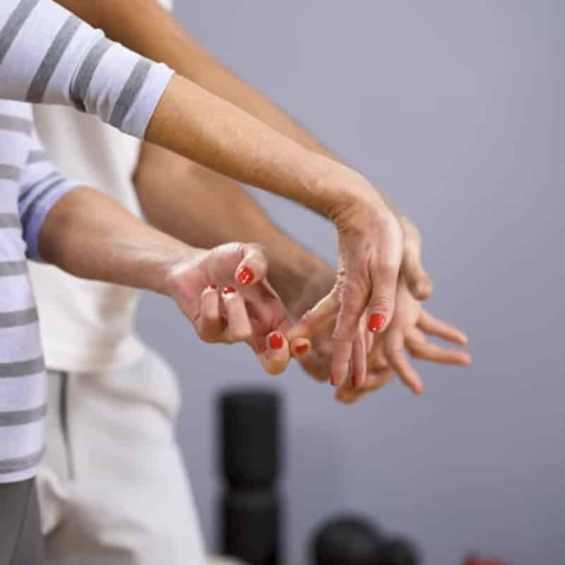 A woman is flexing her wrist, she's pulling her ring finger back with her opposite hand.