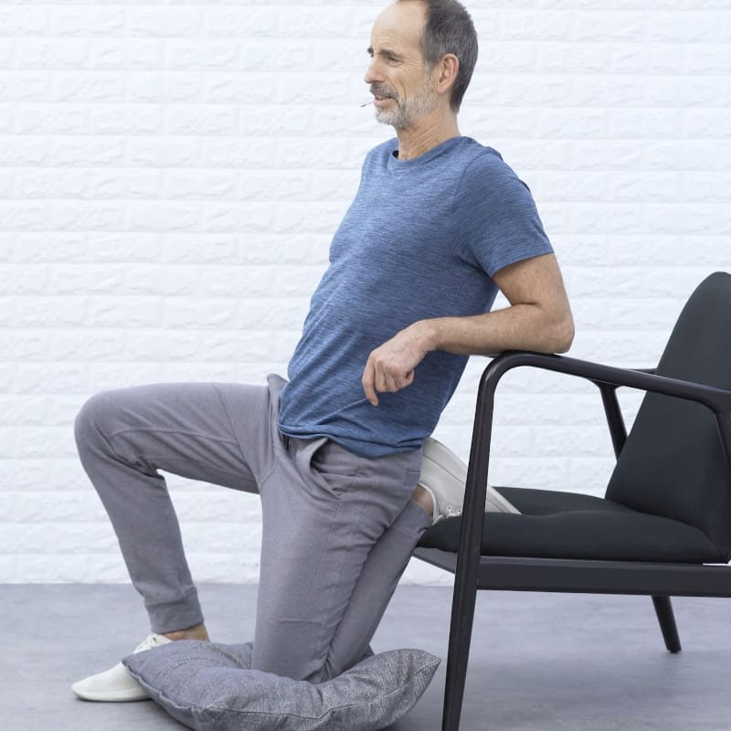 Roland Liebscher-Bracht is kneeling on his left knee in front of a chair.