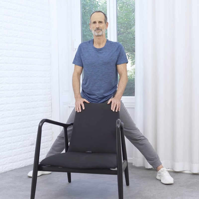 Roland Liebscher-Bracht is standing behind a chair in a wide stance.