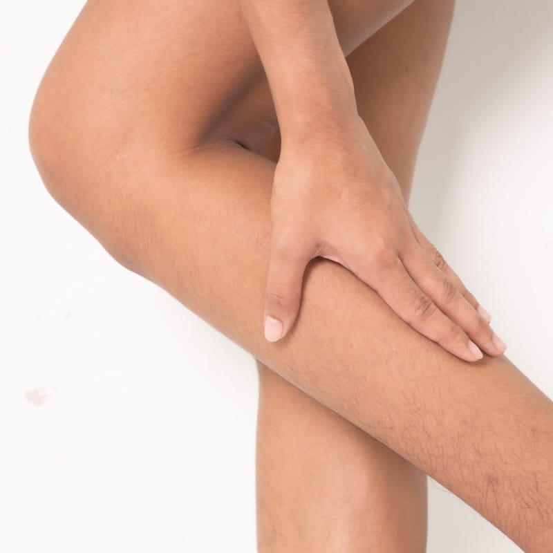 Closeup of a person touching their calf.