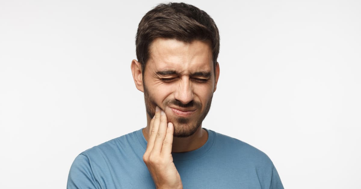 A man is touching his jaw.