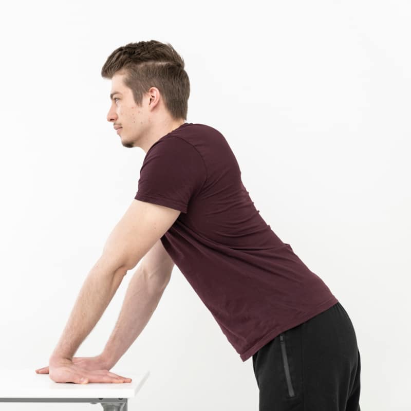 A man is stretching his wrist on a table.